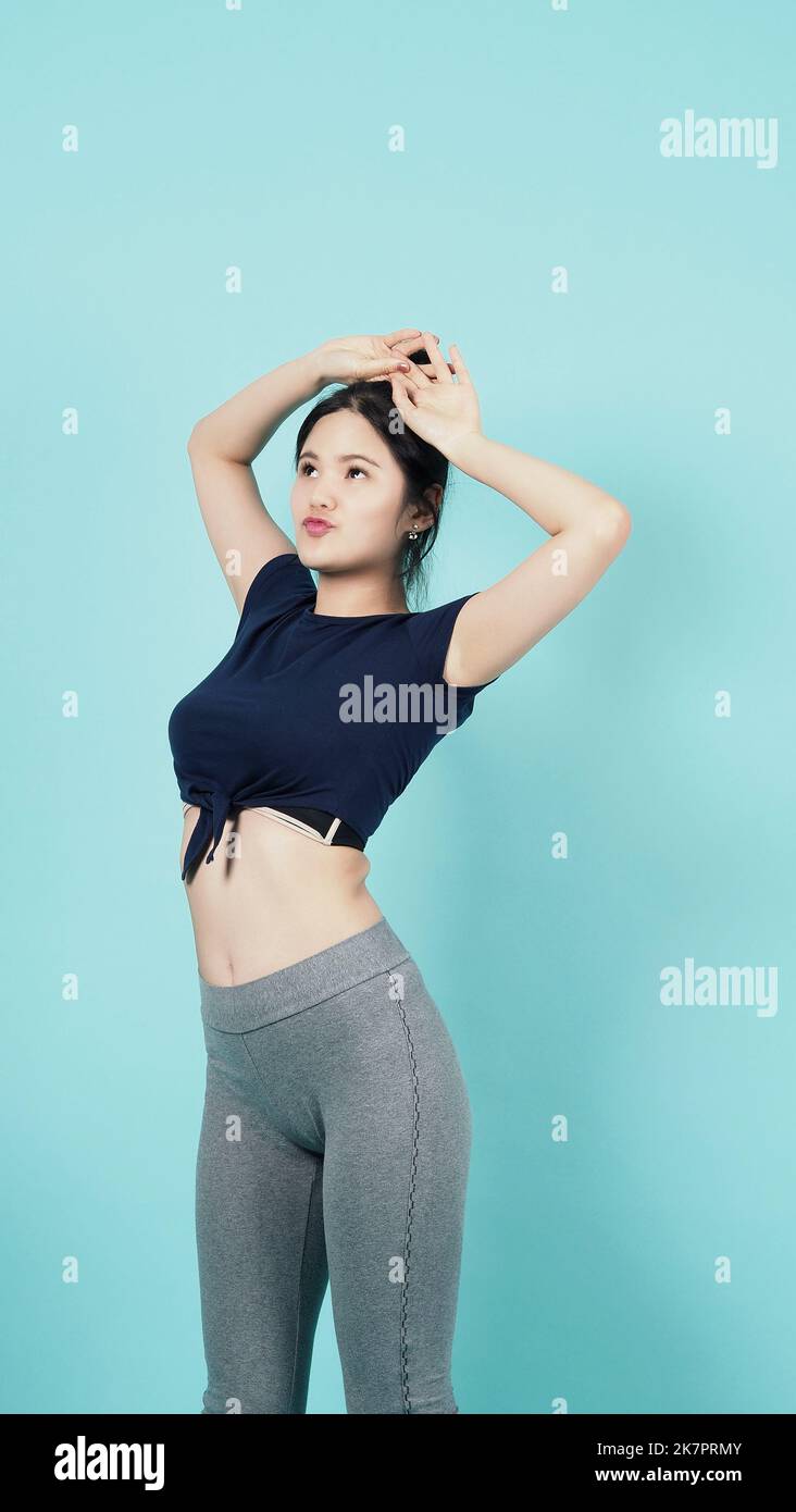Fitness Sportbekleidung Frau lächeln und posieren Körperübungen vor der Kamera isoliert auf blaugrünem Hintergrund. Perfekter Körper sportliche Frau entspannt nach dem Training. Stockfoto