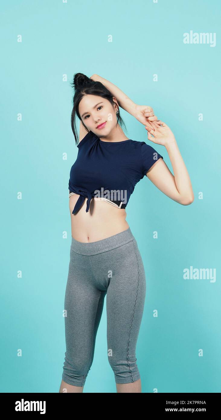 Fitness Sportbekleidung Frau lächeln und posieren Körperübungen vor der Kamera isoliert auf blaugrünem Hintergrund. Perfekter Körper sportliche Frau entspannt nach dem Training. Stockfoto