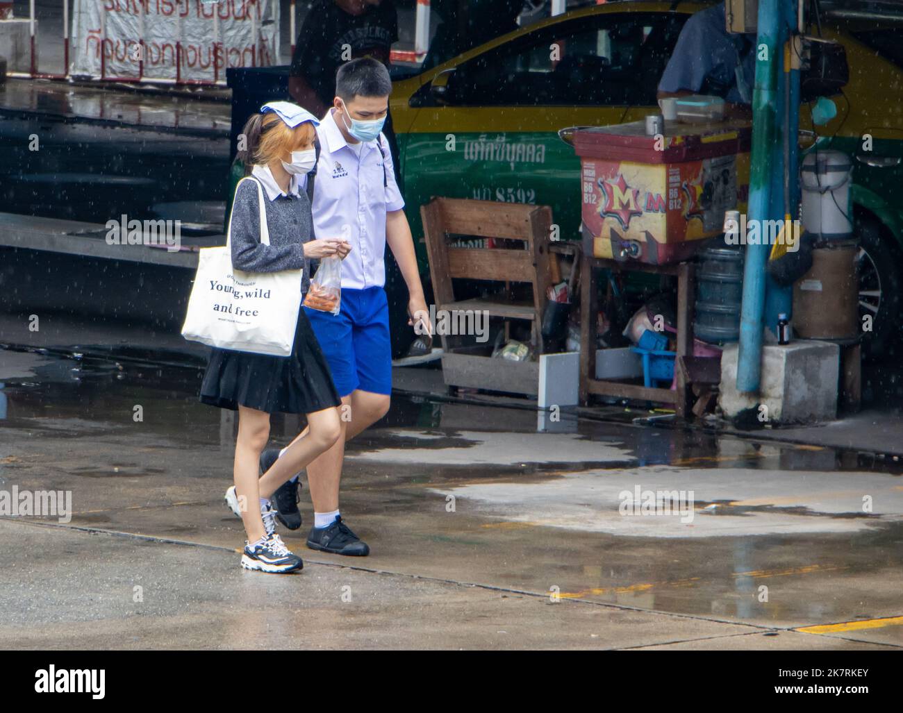 SAMUT PRAKAN, THAILAND, SEP 23 2022, Ein Junge und ein Mädchen in Schuluniformen gehen auf einer nassen Straße Stockfoto