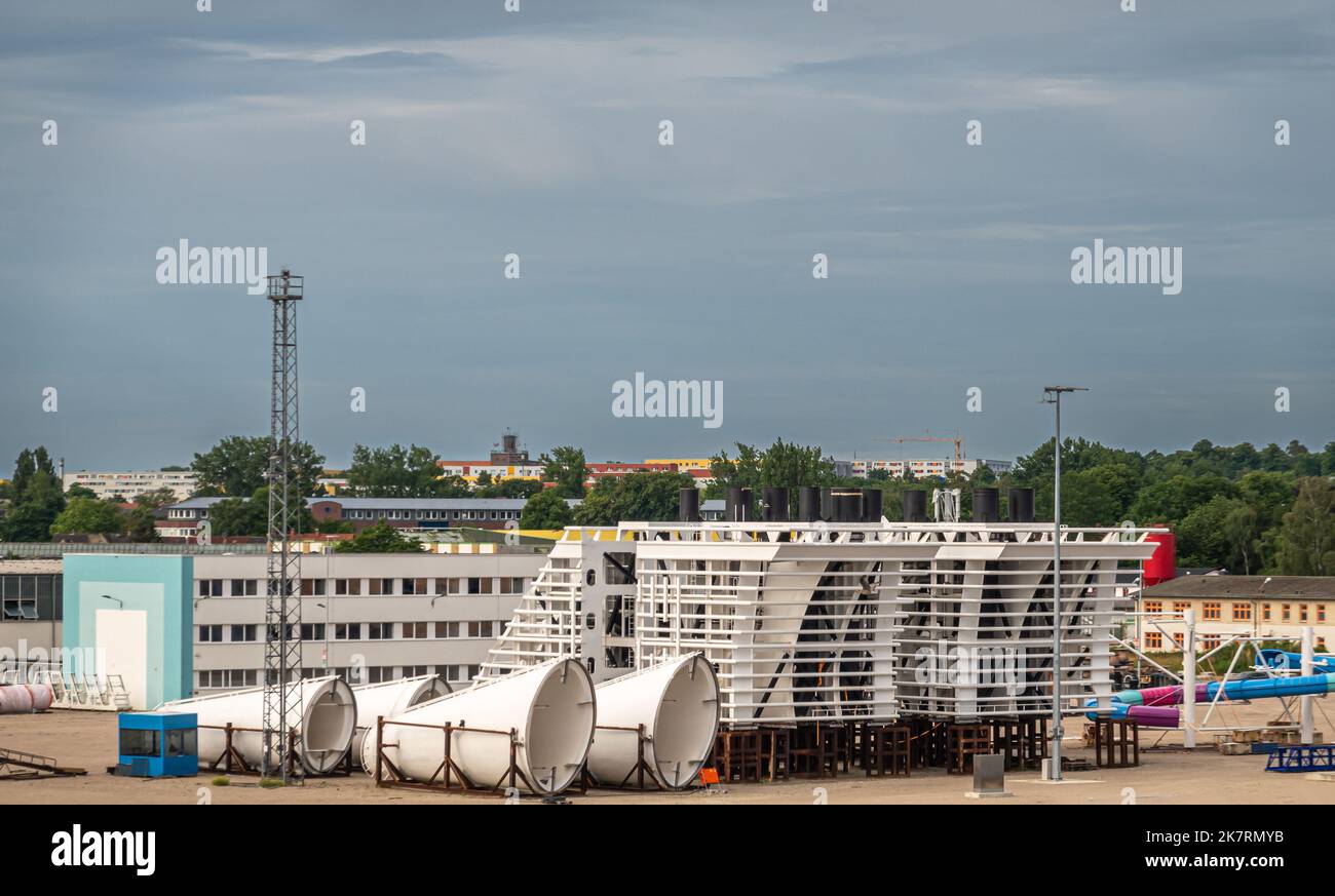 Deutschland, Wismar - 13. Juli 2022: Westhafen-Dock mit großen weißen Schiffbauteilen auf Kai- und Bürogebäuden hinter blauer Wolkenlandschaft Stockfoto