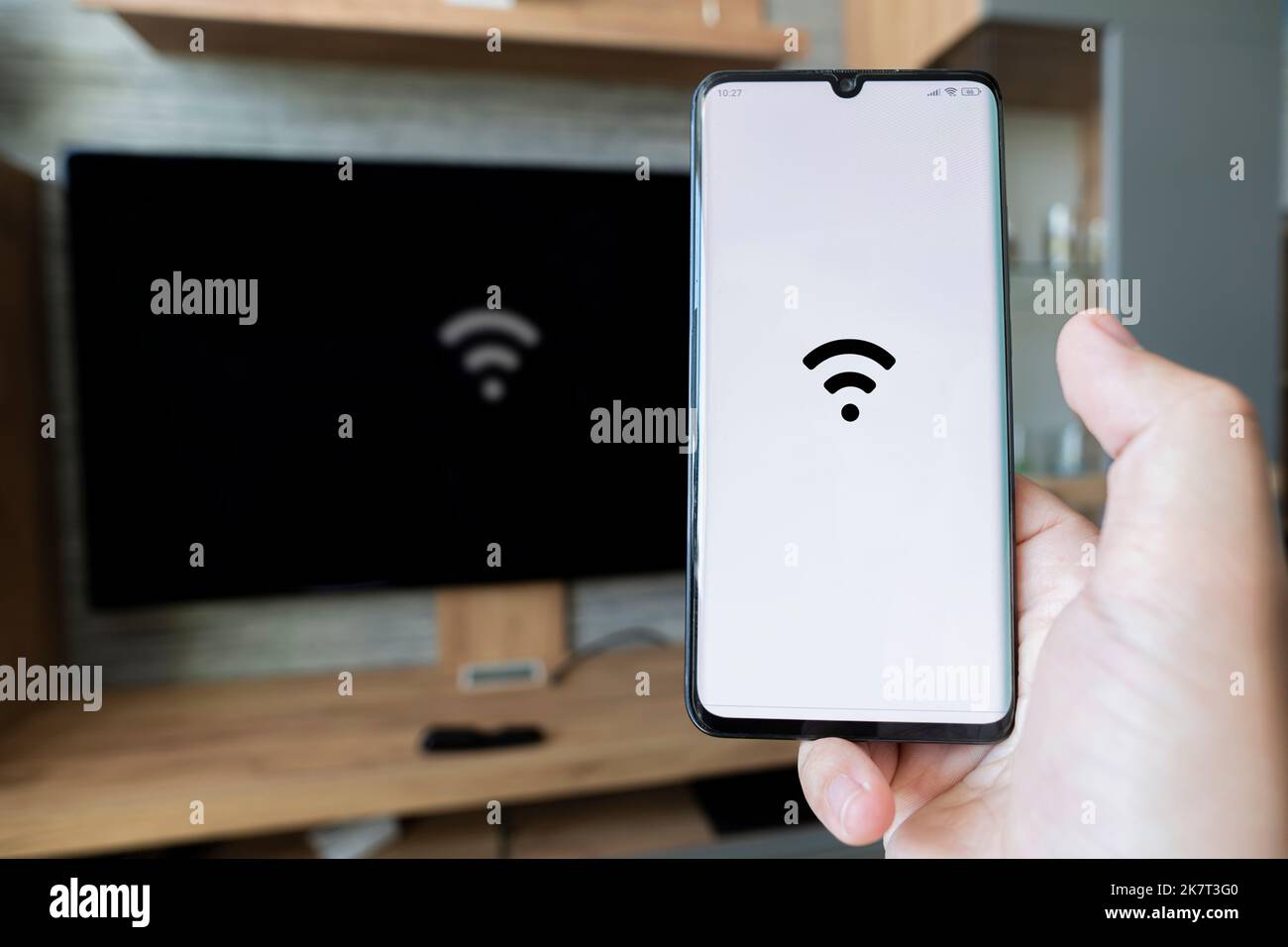 Männliche Hand hält ein Smartphone. Steuern Sie TV mit Smartphone. Konnektivität zwischen Smart tv und Smartphone über WiFi-Verbindung. Um die I zu verteilen Stockfoto