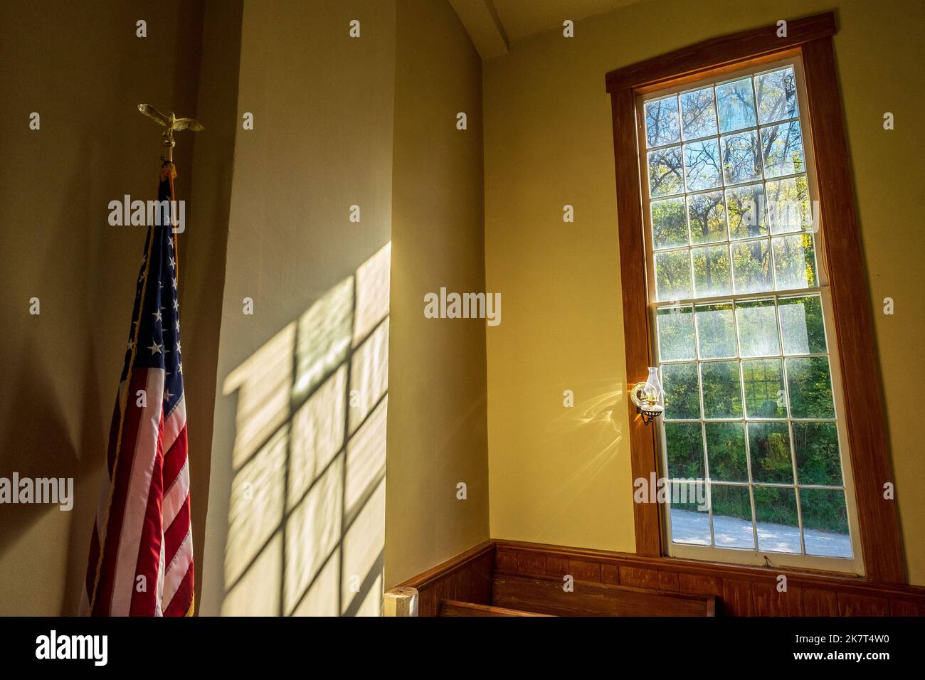 Amerikanische Flagge, Sonnenlicht durch ein Fenster, an einer historischen presbyterianischen Kirche in Bentonsport, Iowa, USA Stockfoto