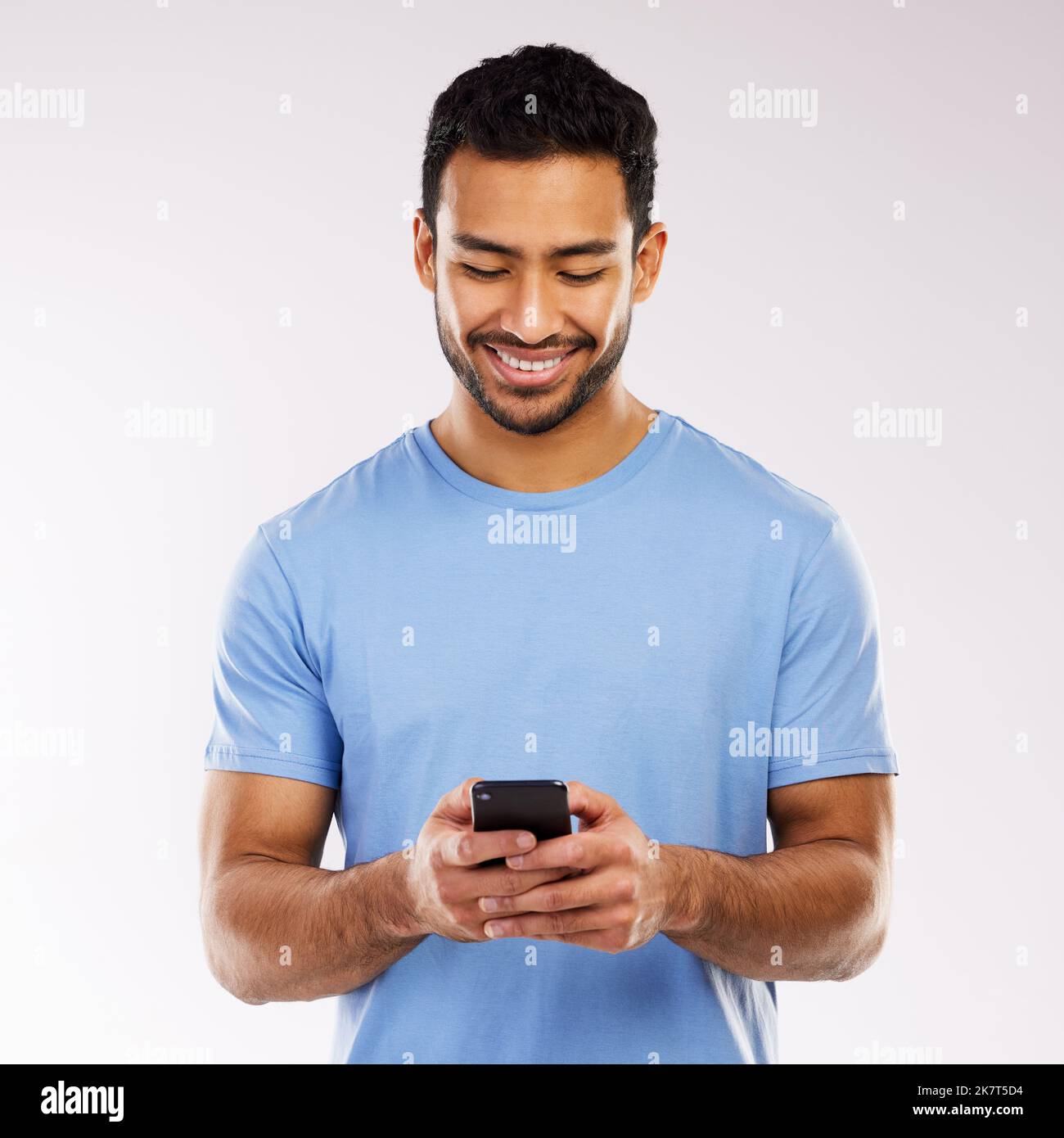 Der Meme-König. Studio-Aufnahme eines jungen Mannes mit einem Telefon vor grauem Hintergrund. Stockfoto