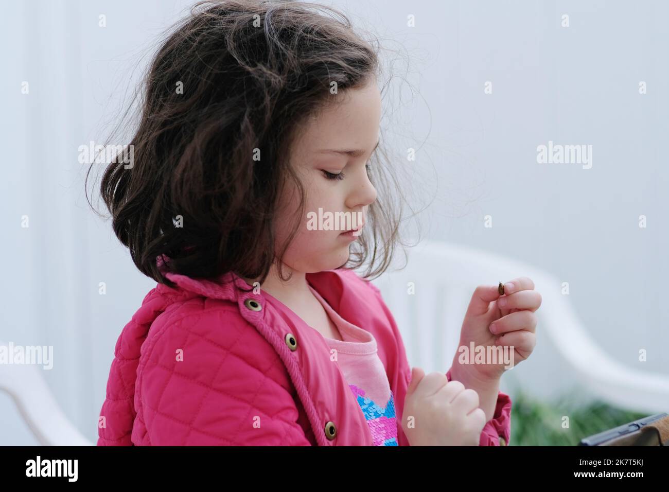 Hübsches junges Mädchen ist mit kleinen Objekten im Hinterhof herumbasteln Stockfoto