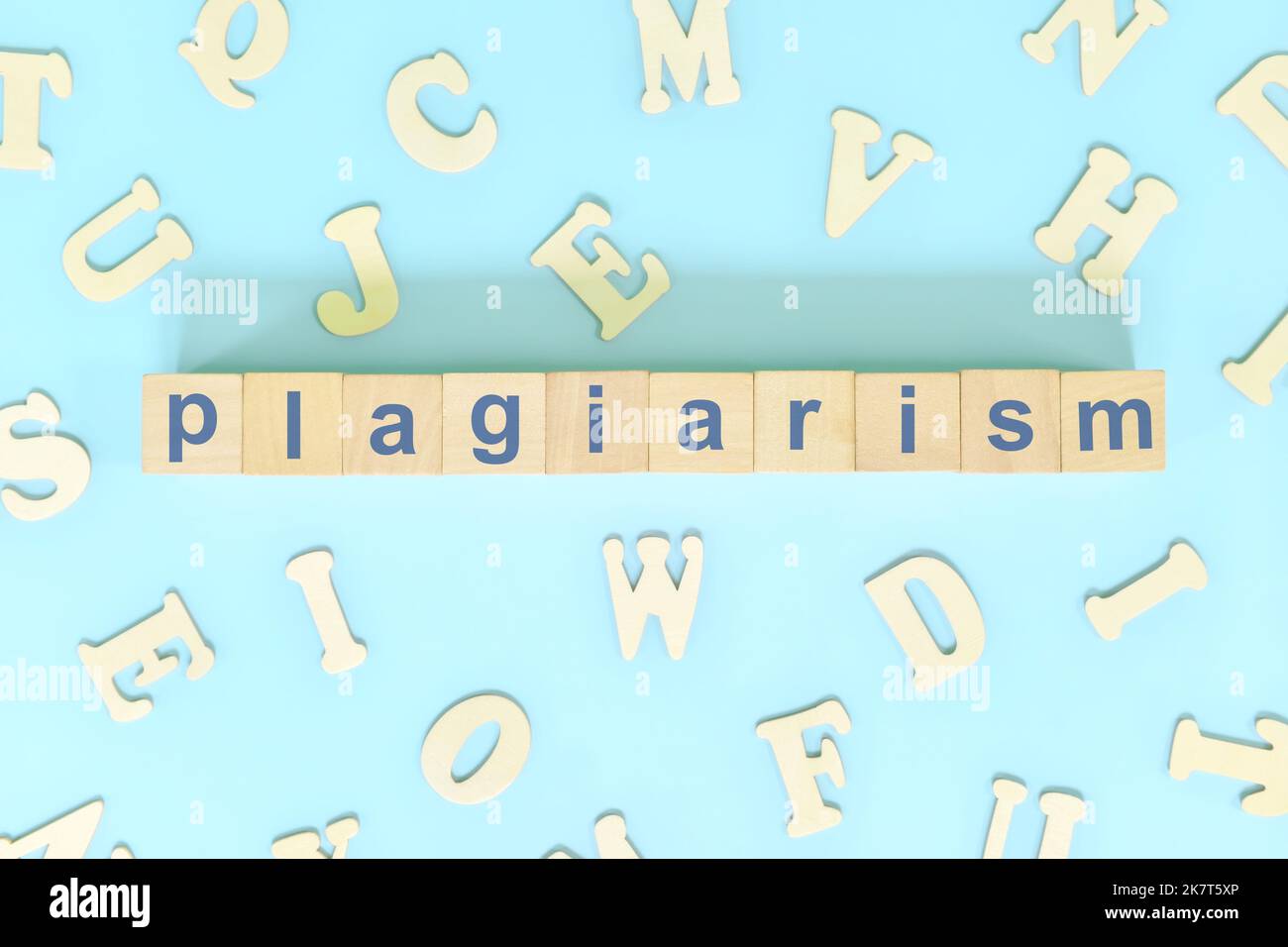 Plagiatkonzept. Worttypografie auf Holzblöcken kreative flache Lay-Komposition auf blauem Hintergrund. Stockfoto