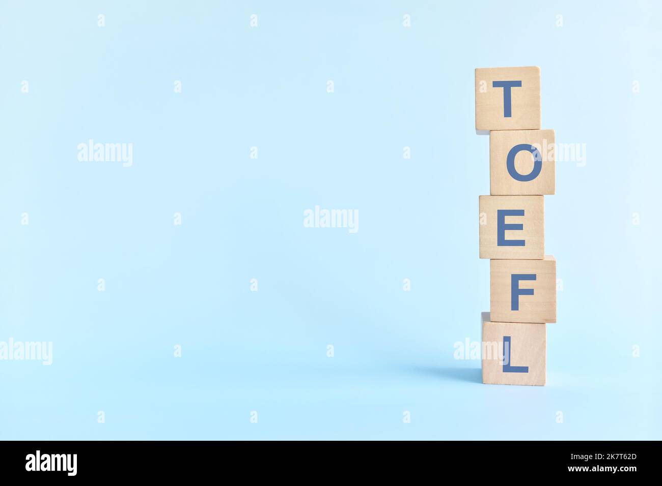 TOEFL oder Test von englisch als fremdsprachiges Prüfungssystem Prüfungskonzept. Holzblöcke Typografie flach lag auf blauem Hintergrund. Stockfoto