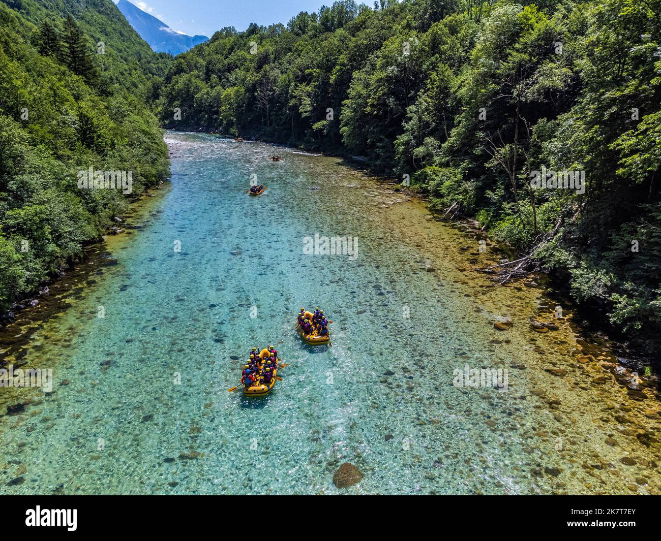 Soca-Tal, Slowenien - Luftbild des smaragdgrünen Alpenflusses Soca mit Raftingbooten, die an einem sonnigen Sommertag den Fluss hinunter fahren, mit grünem Wasser Stockfoto