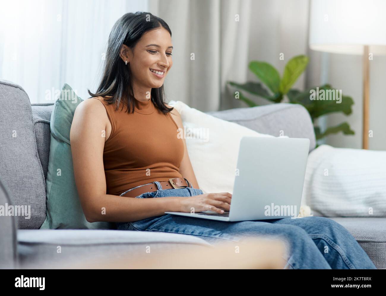 Lockdown schränkte die Zuweisungen nicht ein. Eine attraktive junge Frau, die allein in ihrem Wohnzimmer sitzt und ihren Laptop benutzt. Stockfoto