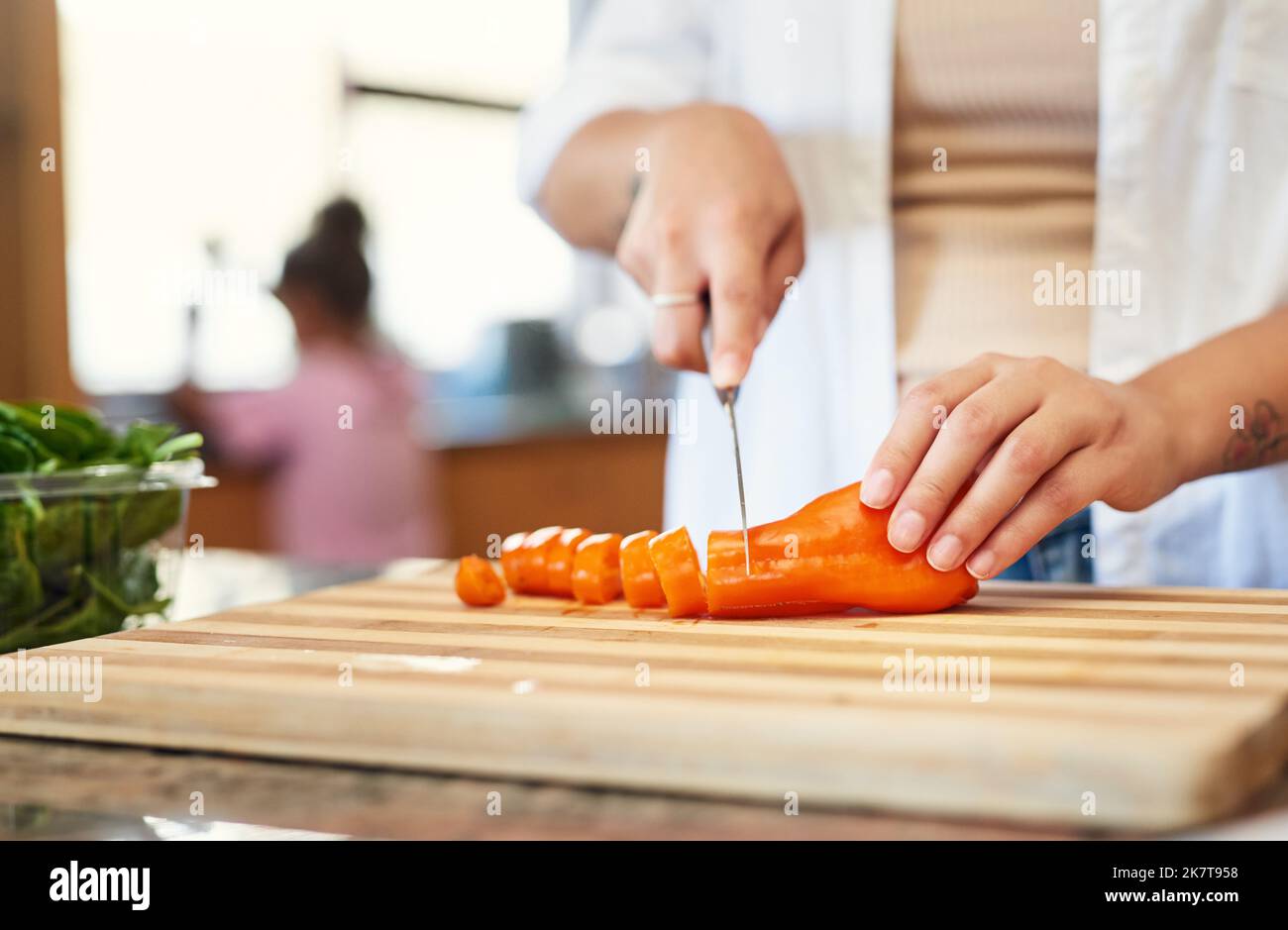 Fügen Sie einfach ein paar Karotten hinzu. Eine Frau hackt zu Hause Karotten. Stockfoto