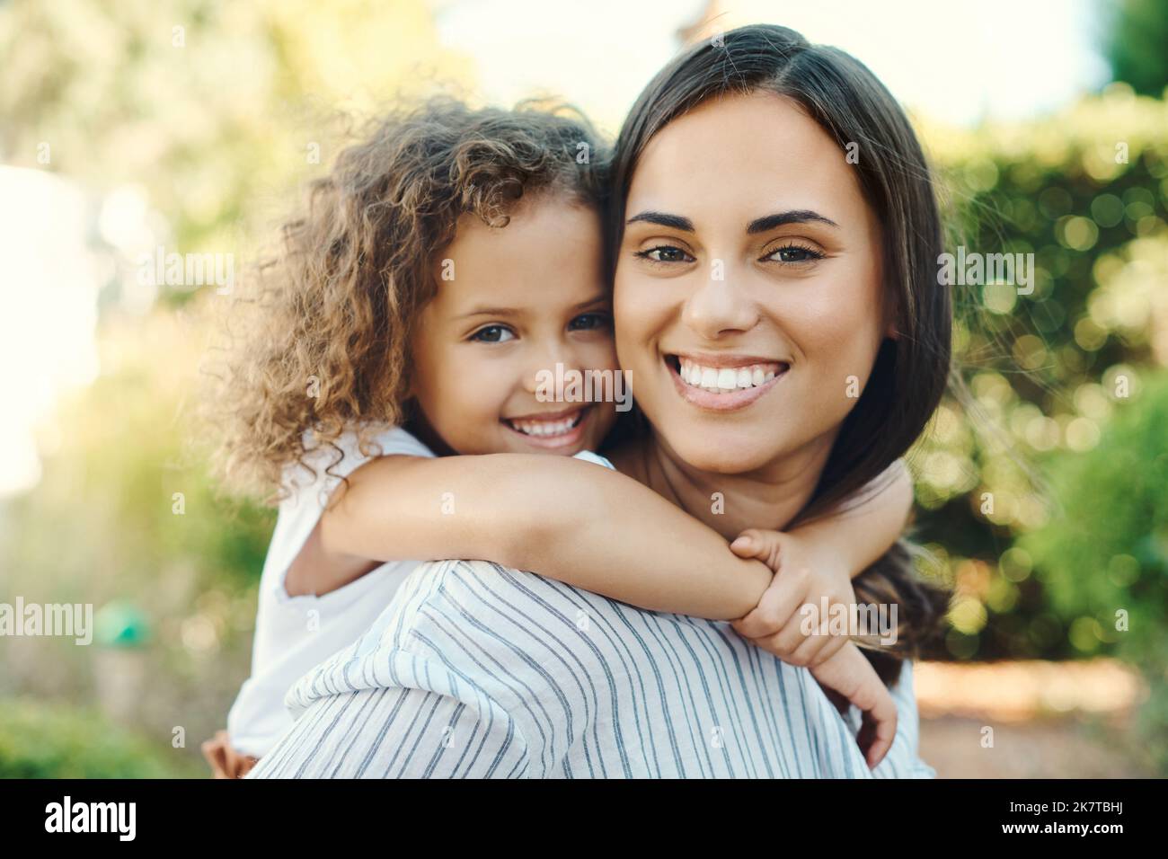 Mama gibt die besten Huckepack Fahrten. Eine junge Frau, die ihrer Tochter eine Huckepack-Fahrt gab. Stockfoto