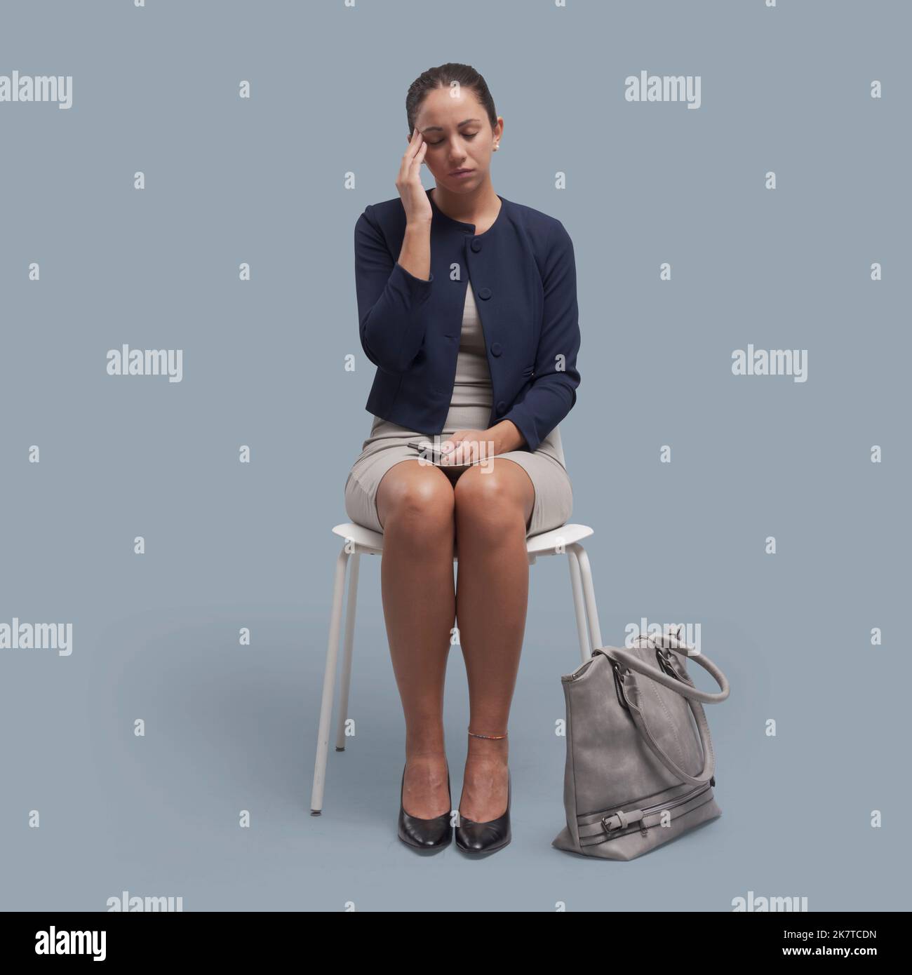 Junge Geschäftsfrau sitzt auf einem Stuhl und hat starke Kopfschmerzen Stockfoto