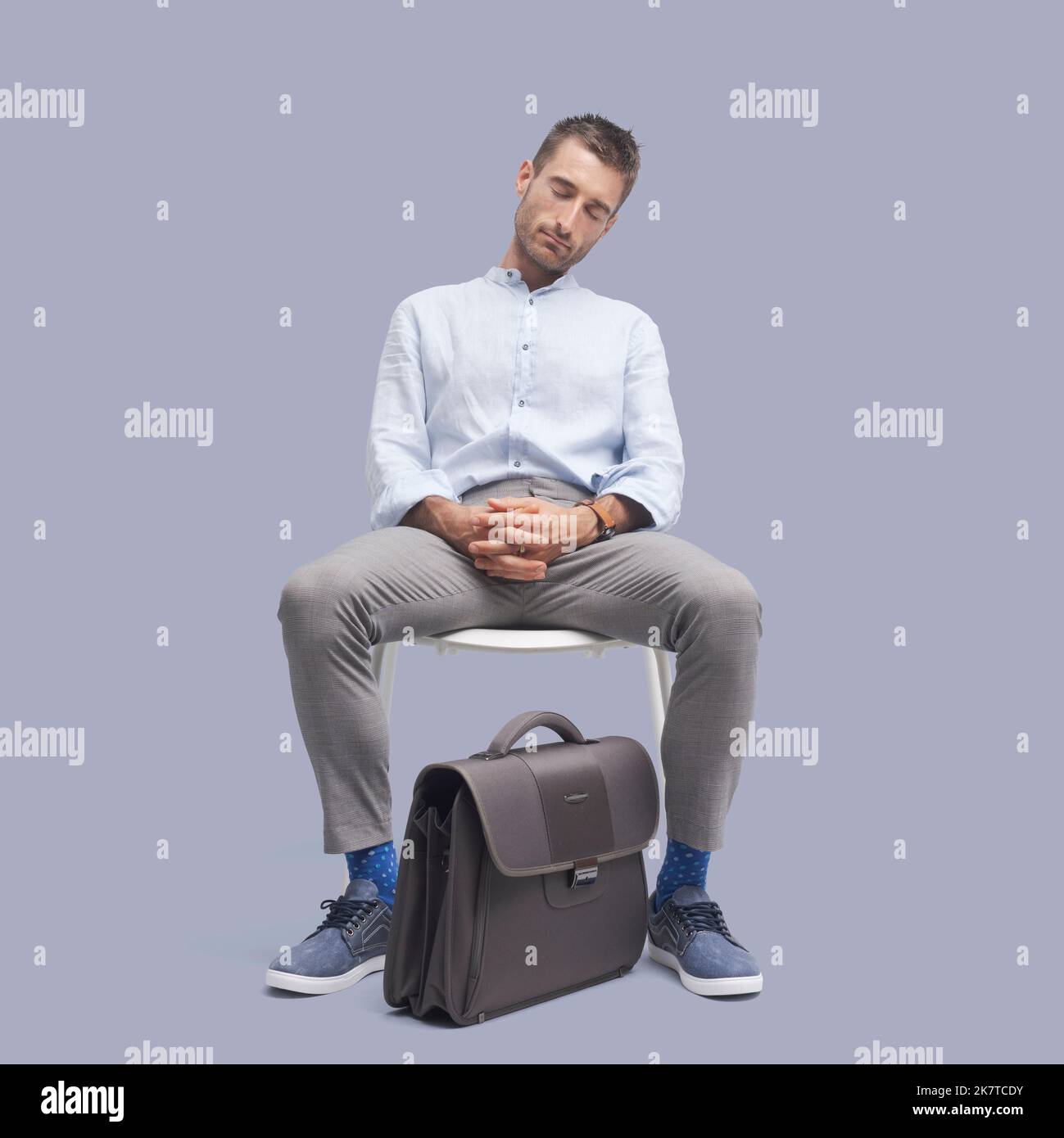 Fauler, müde Geschäftsmann sitzt auf einem Stuhl und schläft ein Stockfoto