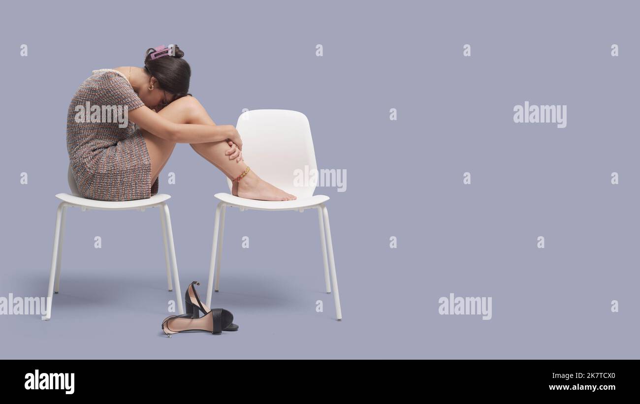 Depressive müde Geschäftsfrau, die auf einem Stuhl sitzt und sich mit den Füßen nach oben ausruht Stockfoto