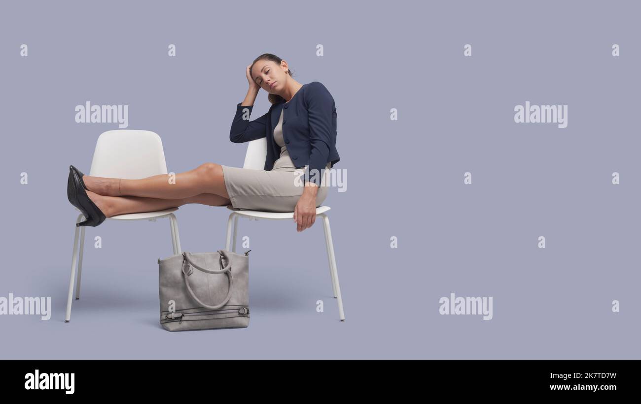 Junge elegante Geschäftsfrau sitzt auf einem Stuhl und schläft Stockfoto