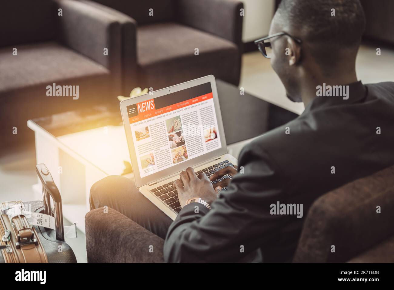 Ein Geschäftsmann las die News-Update-Website in einem Laptop, während er in der Flughafenlounge auf die Reise wartete Stockfoto