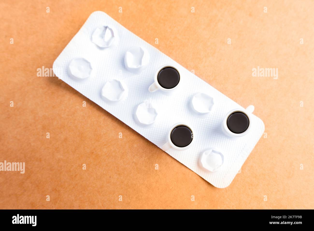 Kleine Kaffeetassen, die isoliert auf einer Tablettenblister platziert wurden. Interaktionskonzept für Medikamente und Kaffee. Stockfoto
