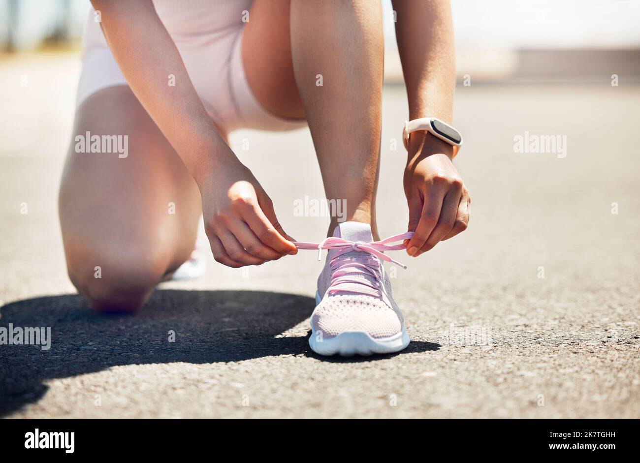 Fitness, Bewegung und Schuhe mit einer Sportlerin, die ihre Schnürsenkel festbindet, während sie auf einer asphaltierten Straße oder Straße läuft. Training, Training und Cardio mit einer Frau Stockfoto