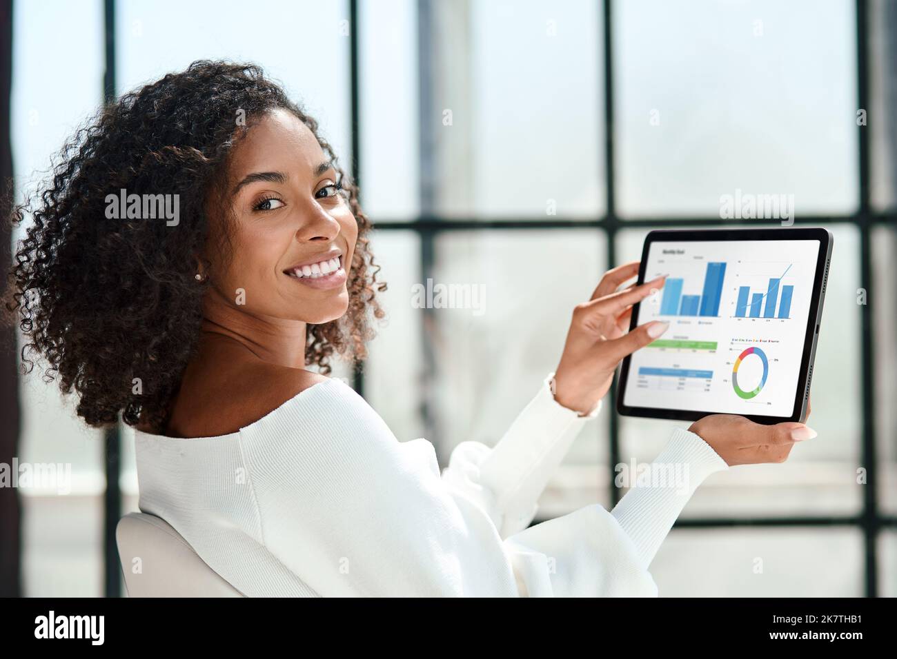 Lächelnde Geschäftsfrau mit einem digitalen Tablet, das auf die Kamera schaut. Stockfoto