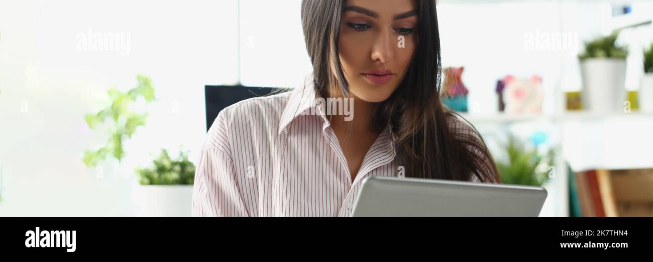 Geballte Dame schaut auf den Tablet-Bildschirm, arbeitet von zu Hause aus, löst Aufgaben aus der Ferne Stockfoto