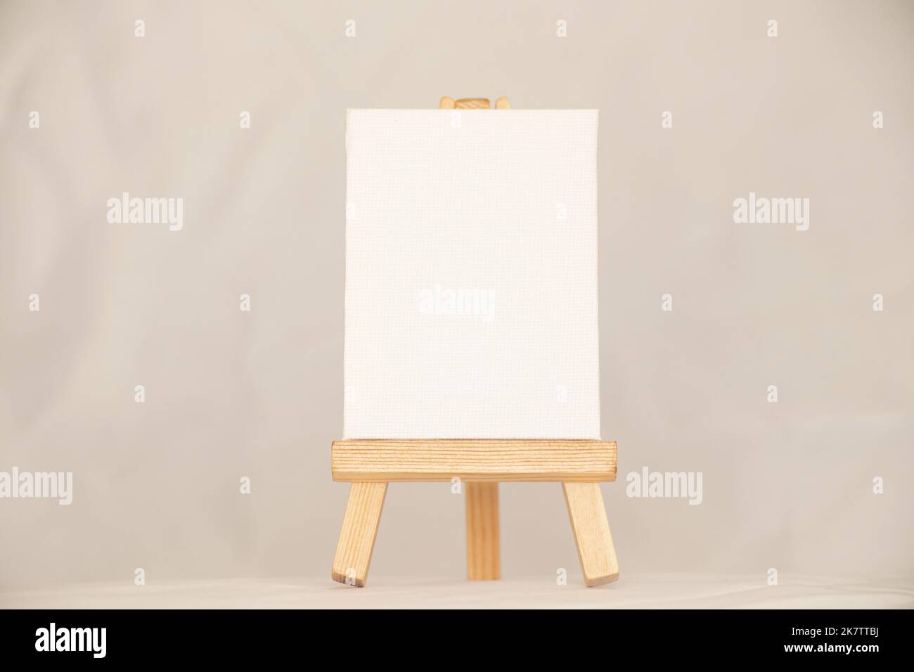 Eine leere weiße Palette steht auf einer hölzernen Staffelei auf einem isolierten Hintergrund, einem Teller und Platz für Text Stockfoto