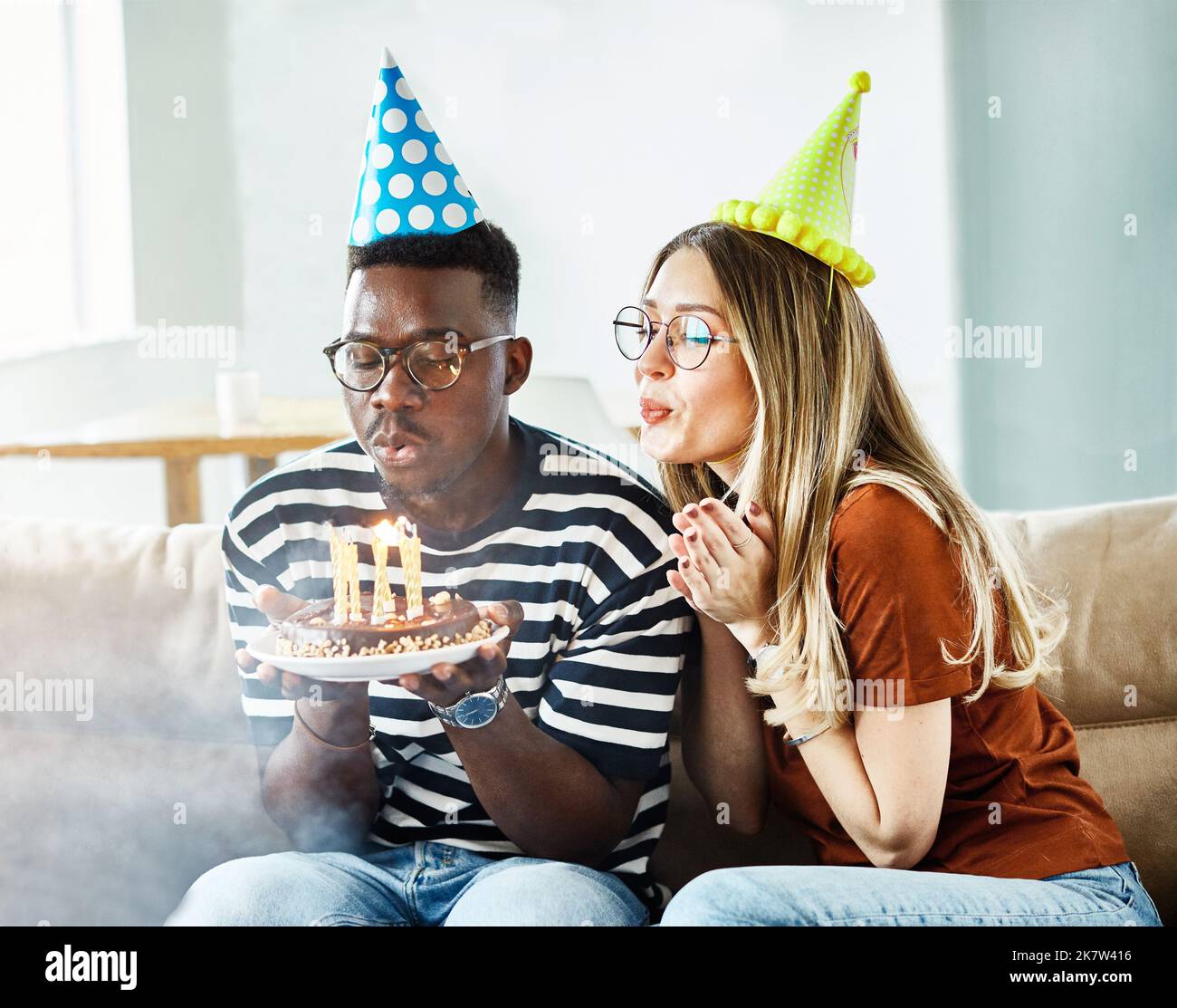 Geburtstag Feier Party Kuchen glücklich Kerze weht Freundschaft Spaß Freund Frau zu Hause lächelnd Lebensstil glücklich Mann fröhlich Stockfoto