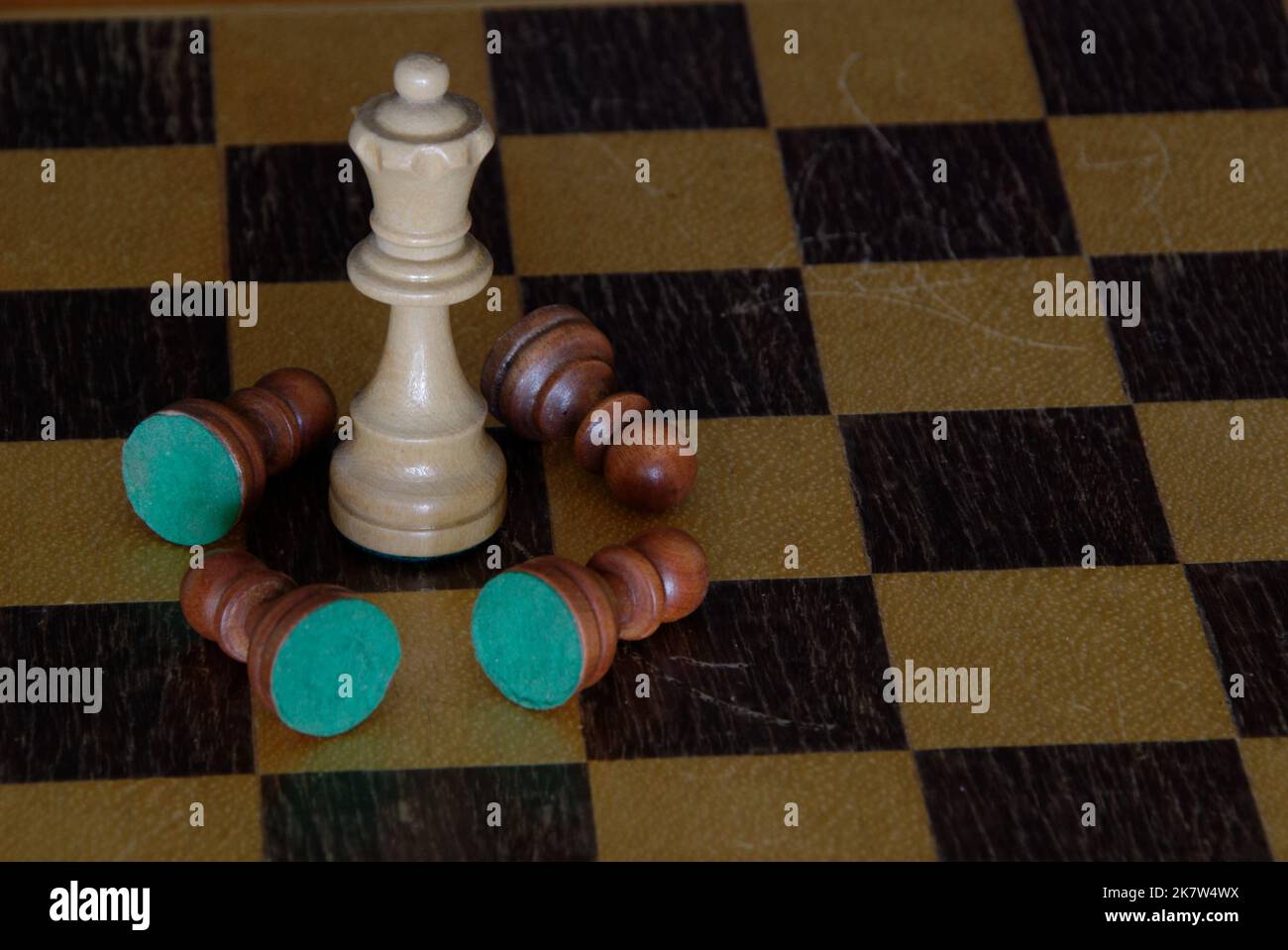 Chess - ein weißer König steht auf dem Schachbrett, umgeben von gefallenen braunen Schachfiguren - es gibt keine anderen Figuren auf dem Brett. Der Kontrast ist stark. Stockfoto