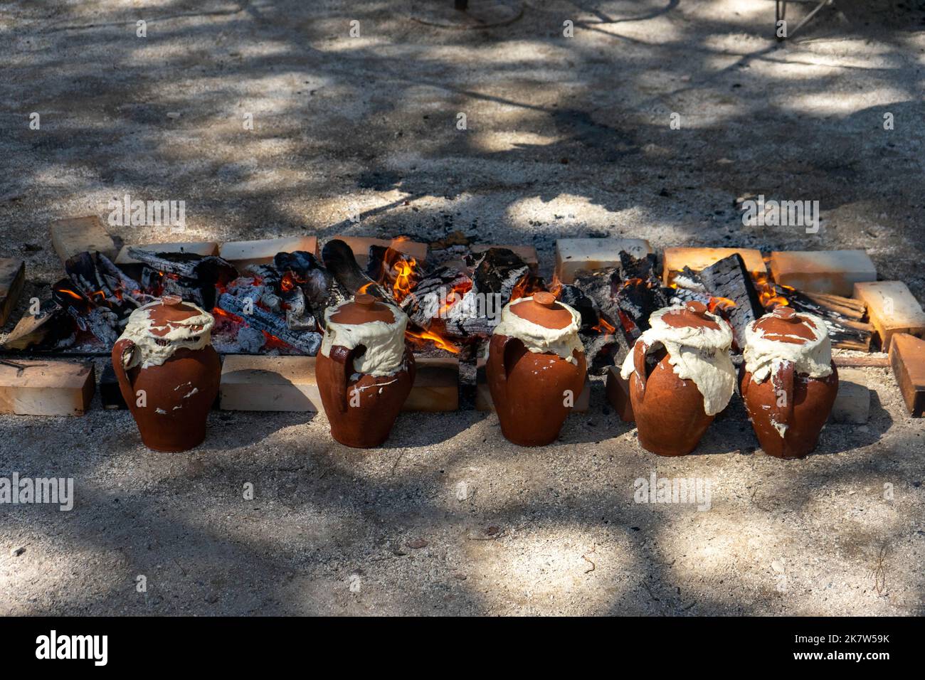 Tontöpfe mit Essen im Inneren werden auf einem langsamen Feuer in einer Feuerstelle auf einem Food Festival in Estoril, Lissabon, Portugal, gekocht. Stockfoto