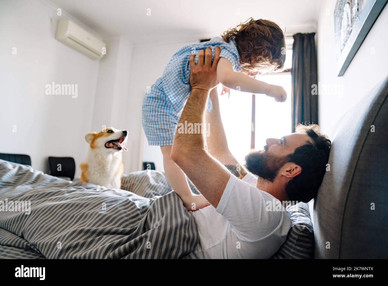 Glückliche Familie, die sich morgens im Bett entspannt und spielt Stockfoto