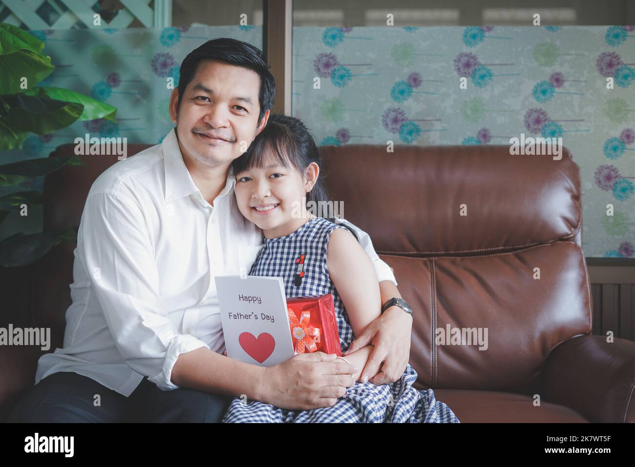 Asiatische kleine Kinder Töchter gratulieren Vater und geben ihm Postkarte Und Geschenkbox mit lächelnd und umarmend.Konzept der glücklichen Vaters Tag Stockfoto