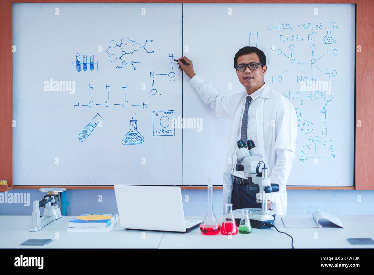 Wissenschaftslehrer schreibt im Klassenzimmer an der Tafel Stockfoto