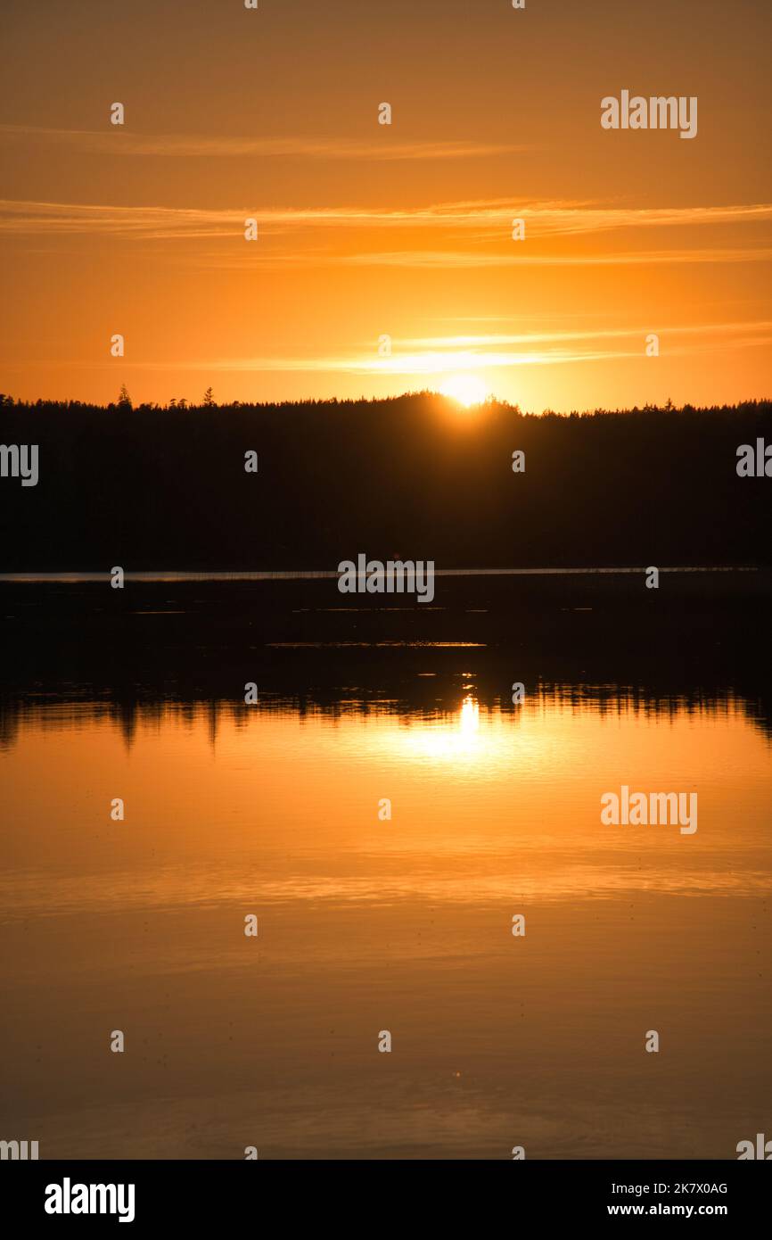 Sonnenuntergang mit Spiegelung auf einem schwedischen See in Smalland. Romantische Abendstimmung. Landschaft aus Skandinavien in der Natur aufgenommen Stockfoto