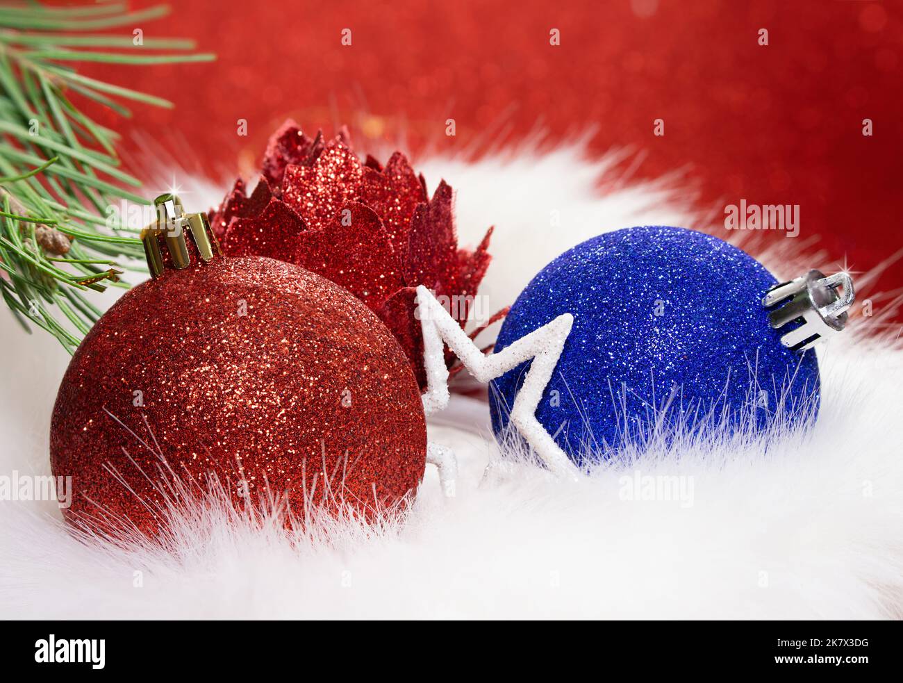 Rote, blau glänzende Kugel und Blume mit Stern mit Tannenzweig auf Fell von hinten verschwommenem Hintergrund. Weihnachten, Neujahr. Speicherplatz kopieren Stockfoto