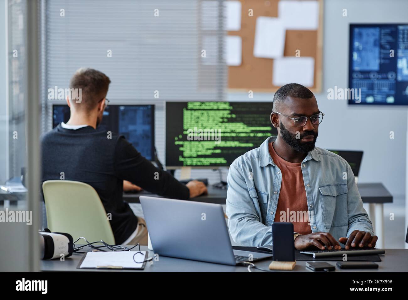 Porträt eines schwarzen Mannes, der Computer verwendet, während er Software im Büro programmiert, Platz kopiert Stockfoto