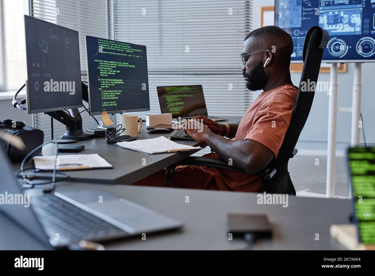 Seitenansicht Porträt eines schwarzen Software-Ingenieurs, der mit Computern im High-Tech-Büro arbeitet, Kopierraum Stockfoto