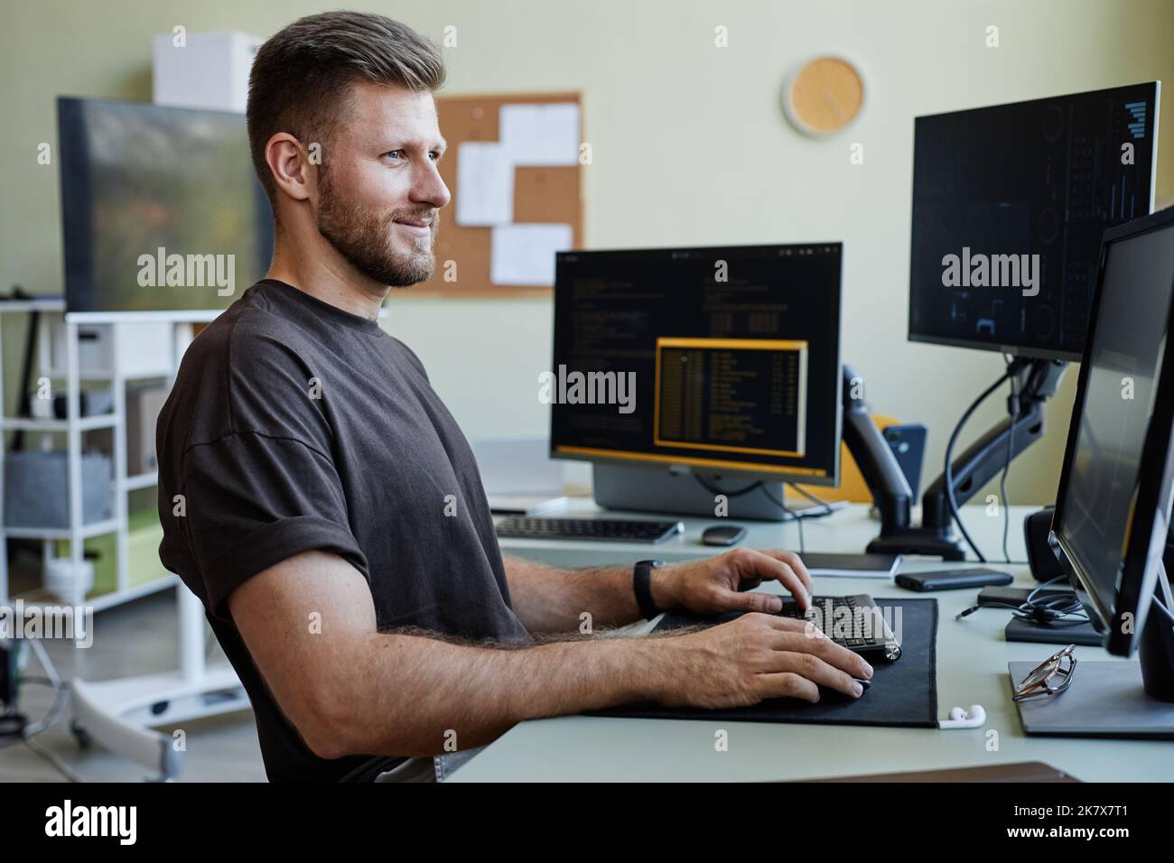 Seitenansicht Porträt eines lächelnden kaukasischen Mannes als Computerprogrammierer, der Code am Büroarbeitsplatz schreibt Stockfoto