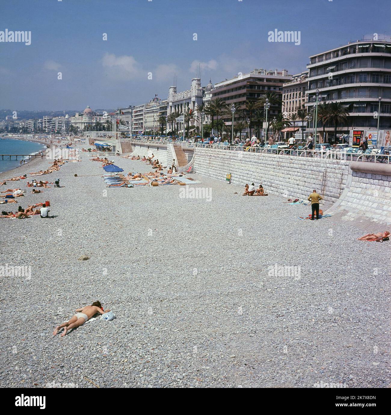 1960s, historisch, Blick auf den Strand und die Küste, Promenade Anglais, Nizza, Frankreich. Ein Schild für Ruhl Plage, ein privates Strandrestaurant, ist zu sehen. Ruhl selbst ist ein öffentlicher Strand an diesem Teil der Mittelmeerküste. Das berühmte Grand Hotel Le Negresco ist in der Ferne zu sehen. Stockfoto