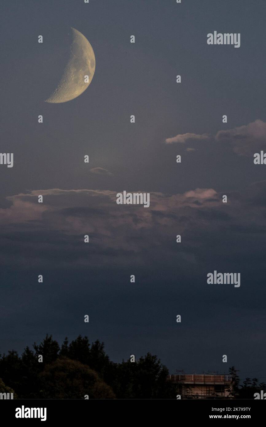 Schöner großer Halbmond am wolkigen Himmel Stockfoto