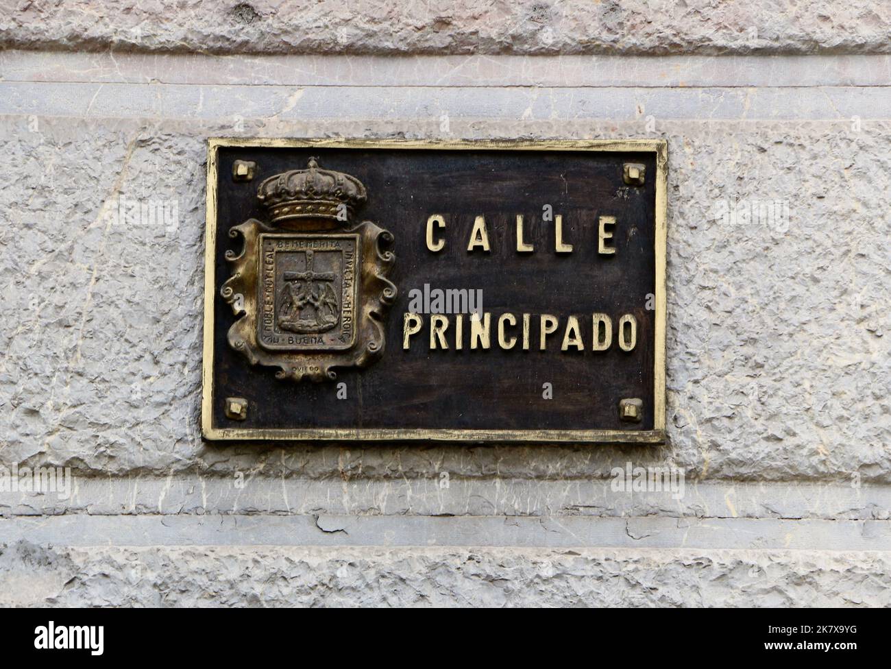 Metall-Straßenschild aus Gold-Metall mit einem Wappenrelief an einer Steinmauer Oviedo Asturias Spanien Stockfoto