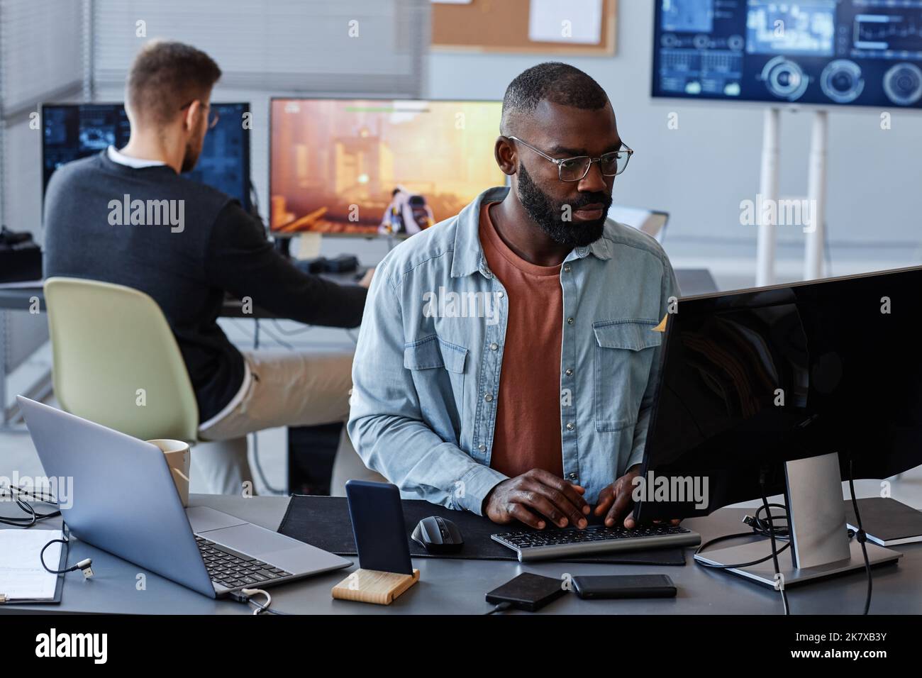Porträt eines schwarzen Mannes, der Computer benutzt, während er Softwarecode im Büro schreibt, Kopierraum Stockfoto