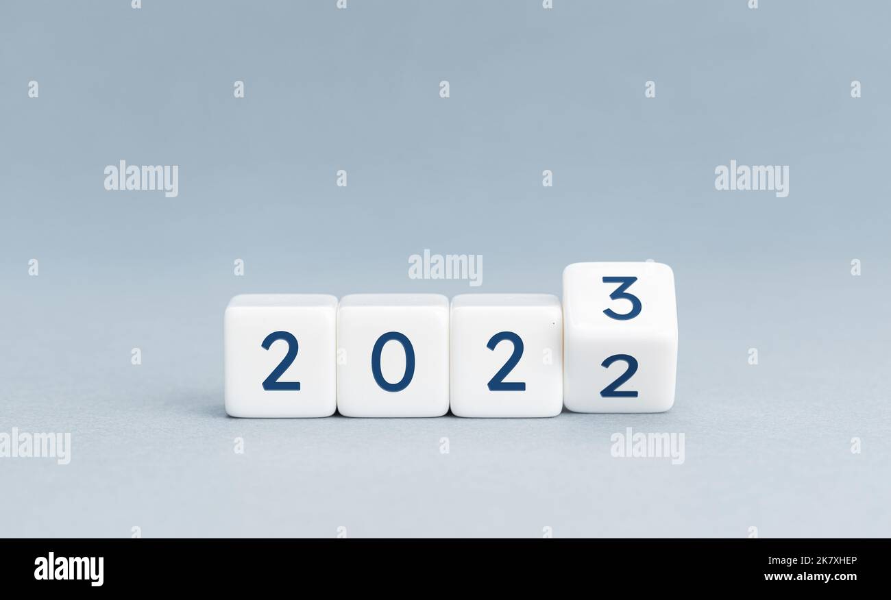 Ändern Sie die Einstellung von 2022 auf 2023 auf Würfelblöcken auf blauem Hintergrund. Das neue Jahr steht vor dem Konzept. Speicherplatz kopieren Stockfoto