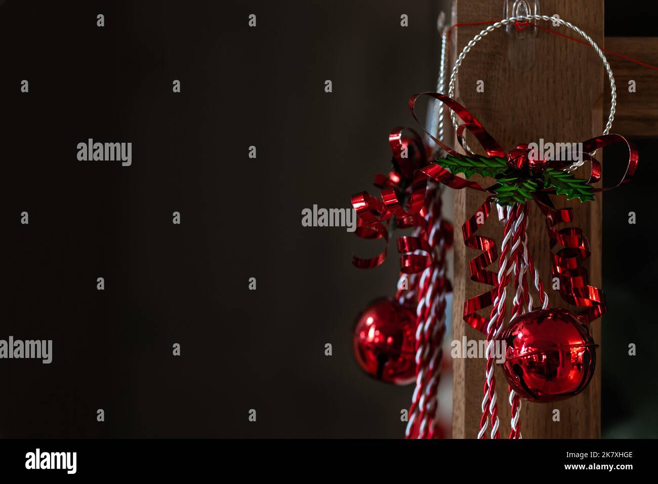 Rote Jingle Bell Weihnachtsdekoration, die auf Holzpfosten aufgehängt wird Stockfoto