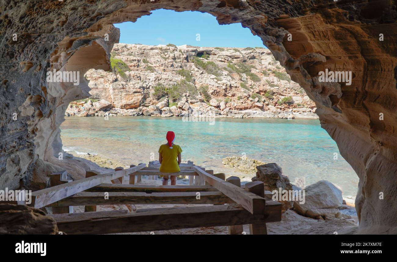 Frau mit weihnachtshut in einer Höhle im Meer auf einer Insel. Weihnachtsferien. Rückansicht Stockfoto