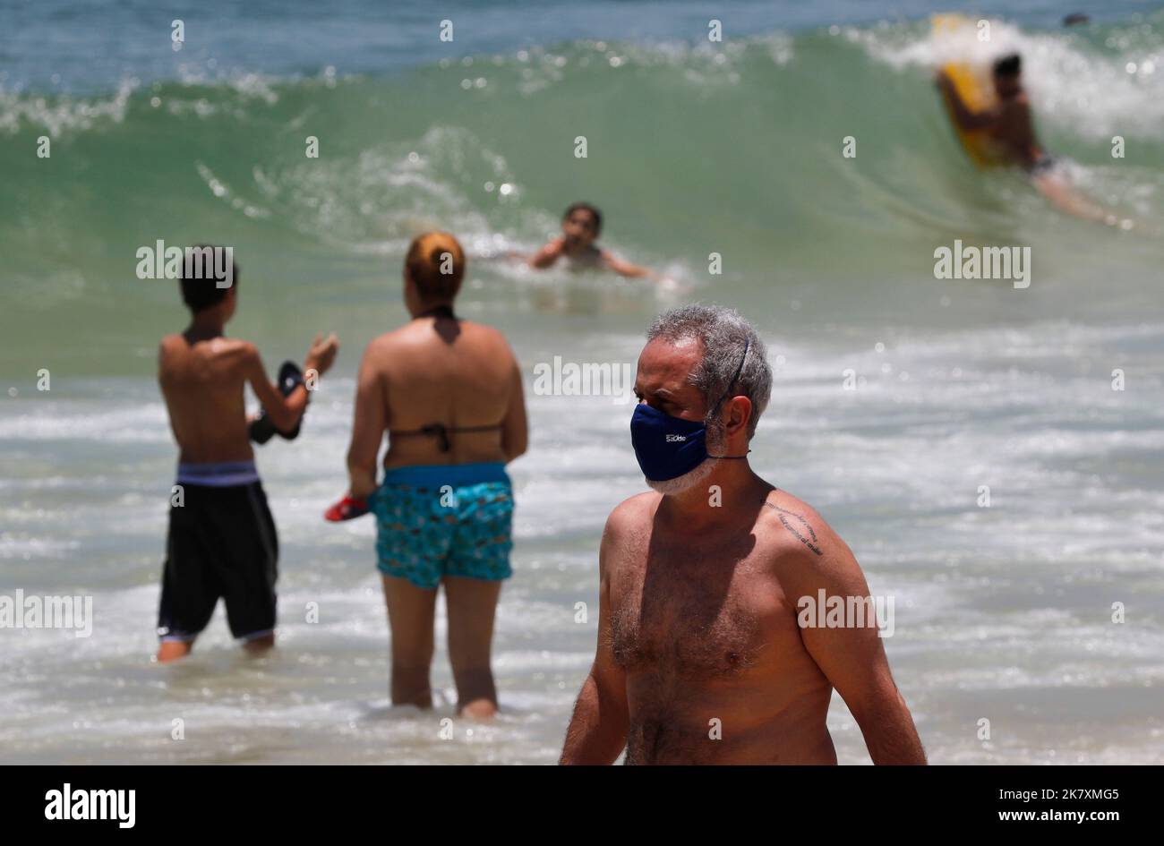 Mann mit Covid-19 Gesichtsmaske am Strand von Cocoaba. Strandgänger sonnen sich am Wochenende in der Nähe der Küste Stockfoto