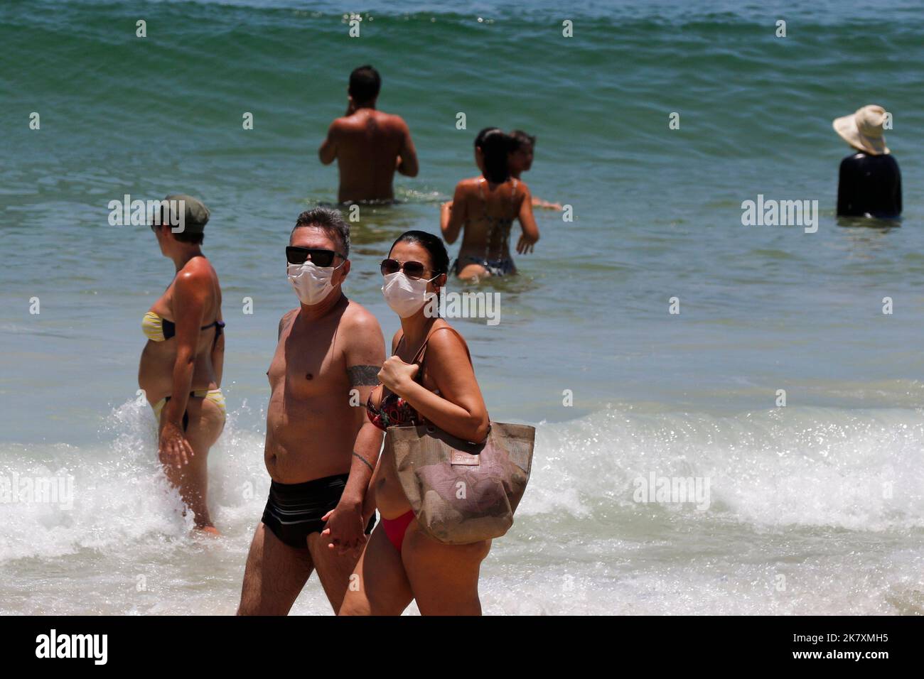 Pärchen trägt Covid-19 Gesichtsmaske am Strand von Cocoaba. Strandgänger sonnen sich am Wochenende in der Nähe der Küste Stockfoto