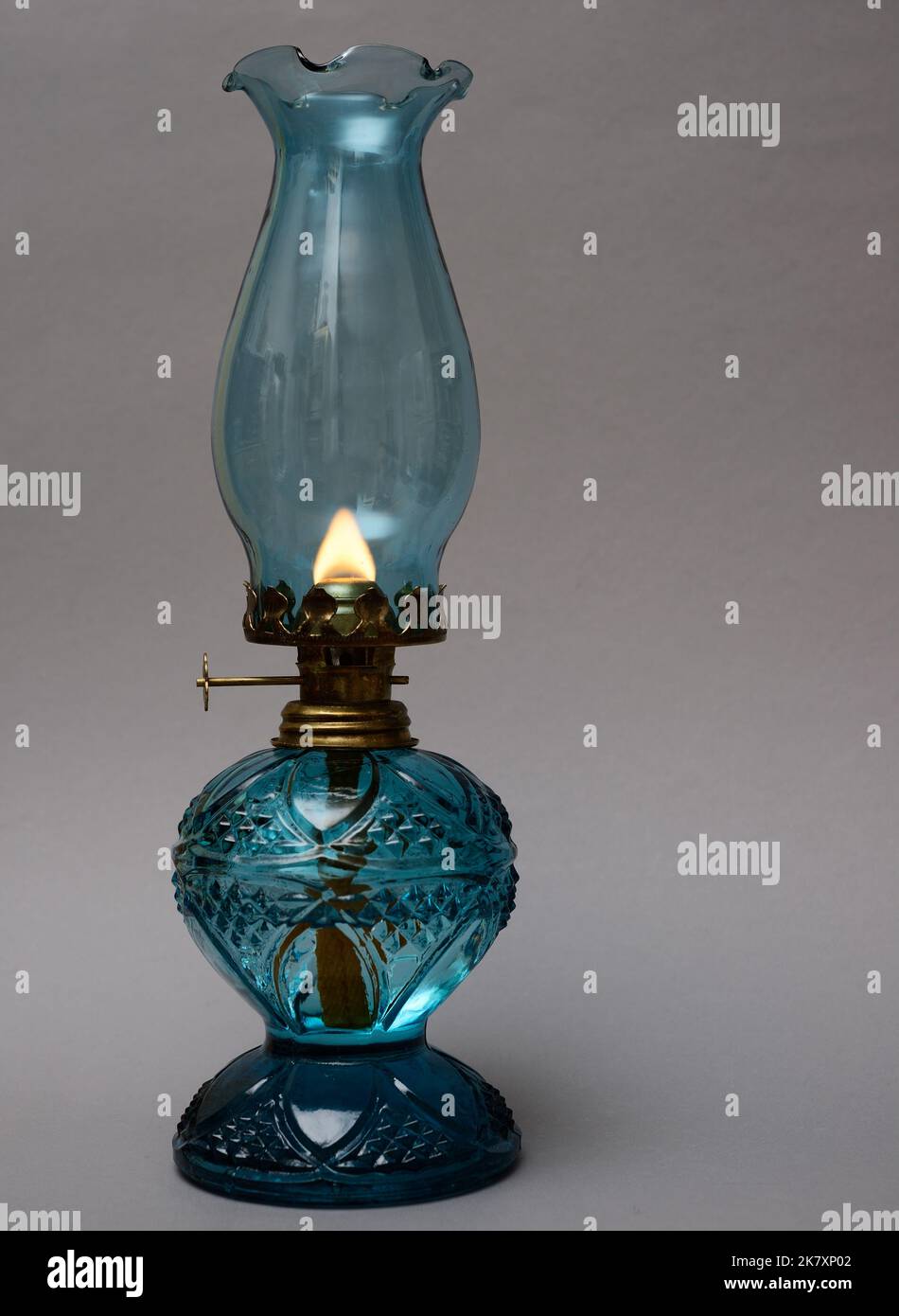 Brennende Vintage Öllampe auf neutralem Hintergrund Stockfoto