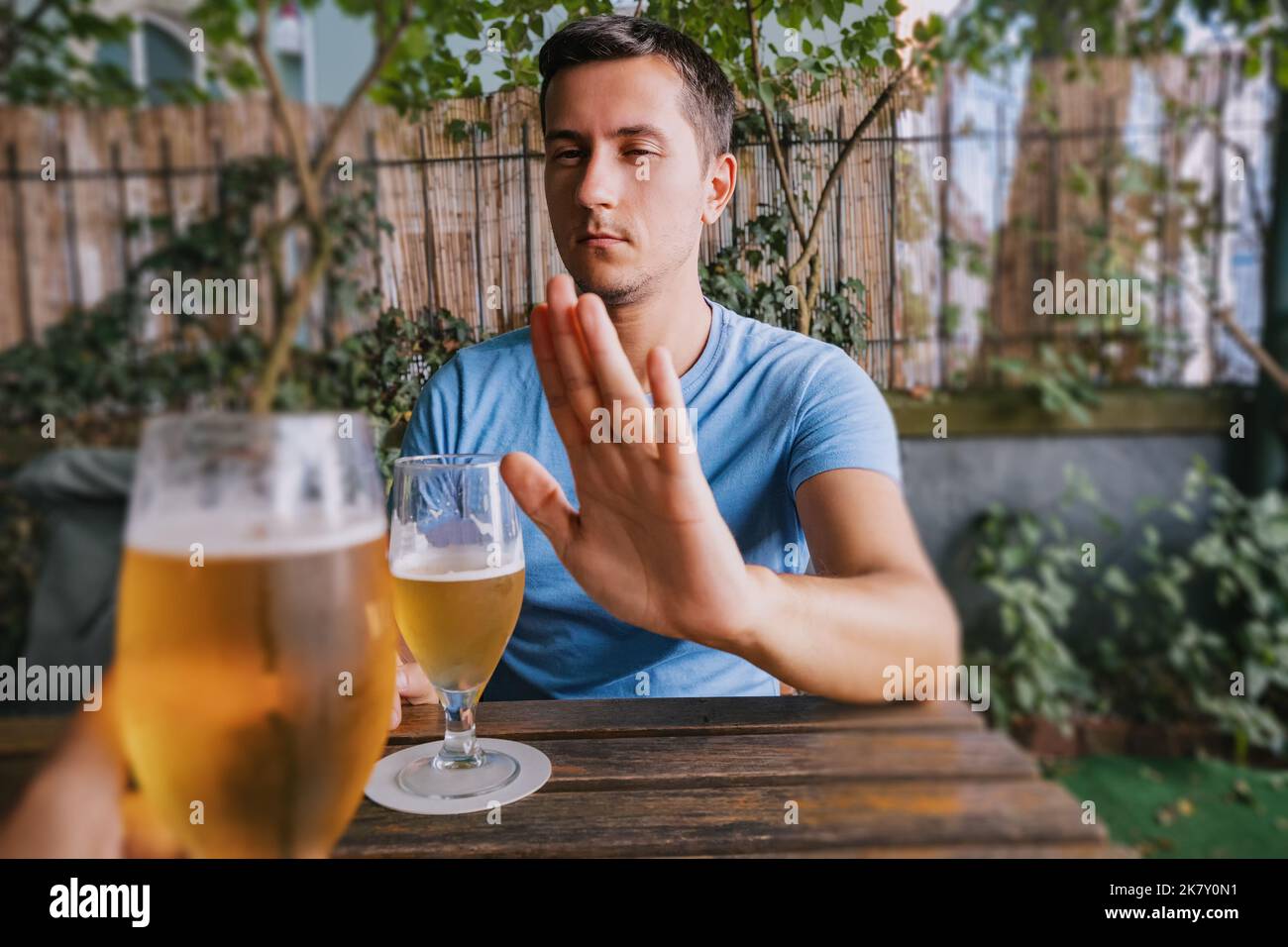 Ein betrunkener Mann verweigert ein zusätzliches Glas Bier an der Bar. Sucht und übermäßiger Alkoholkonsum. Stockfoto