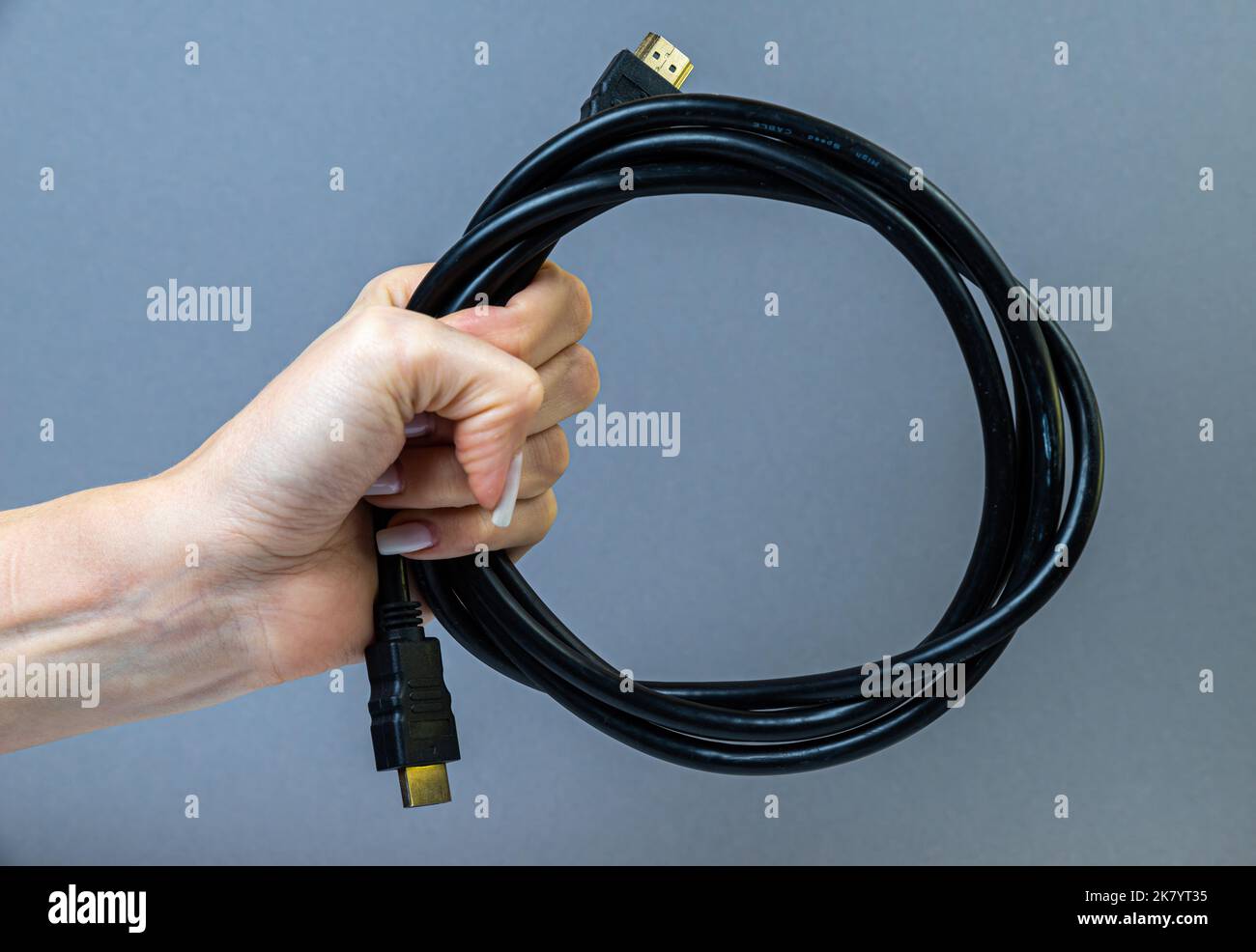 Schwarzes HDMI-Kabel mit Handgriff. Mann hält einen HDMI-Anschluss in der Hand. Nahaufnahme des HDMI-Kabels. Selektiver Fokus und geringe Schärfentiefe. Stockfoto