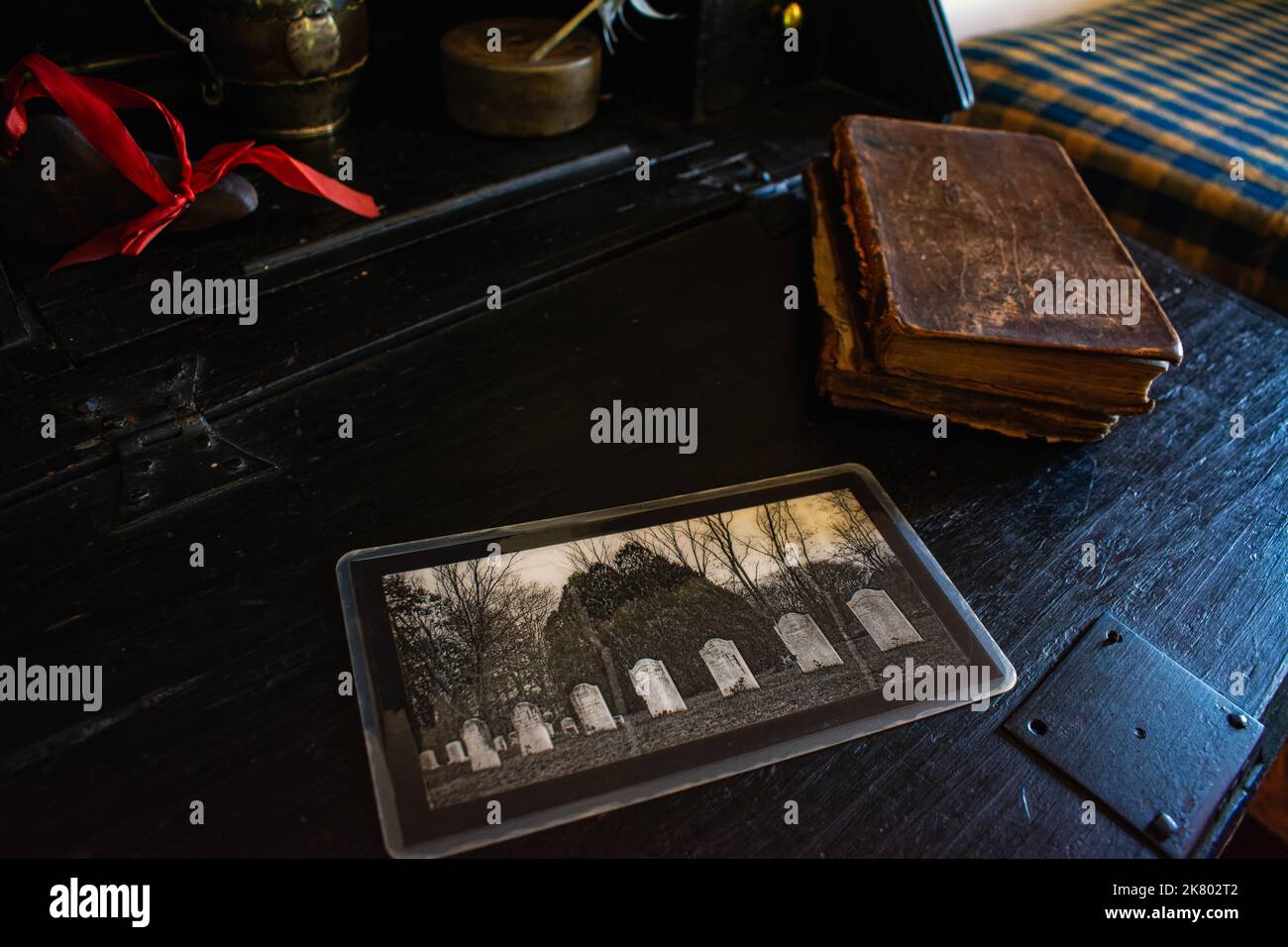 Ein Foto von Grabsteinen liegt auf einem Schreibtisch neben einer warnenden lederbibel bei Cogswell's Grant in Essex, Massachusetts. Stockfoto