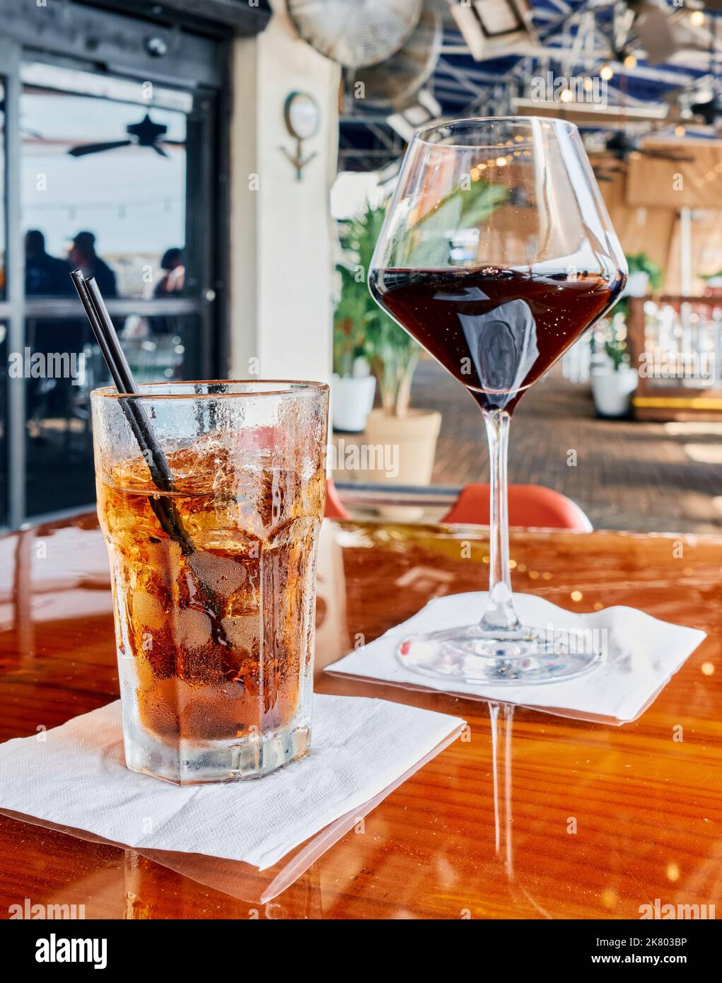 Gemischtes Getränk, möglicherweise Bourbon und Coke oder Rum und Coke, zusammen mit einem Glas Rotwein auf einem Restauranttisch in Destin Florida, USA. Stockfoto