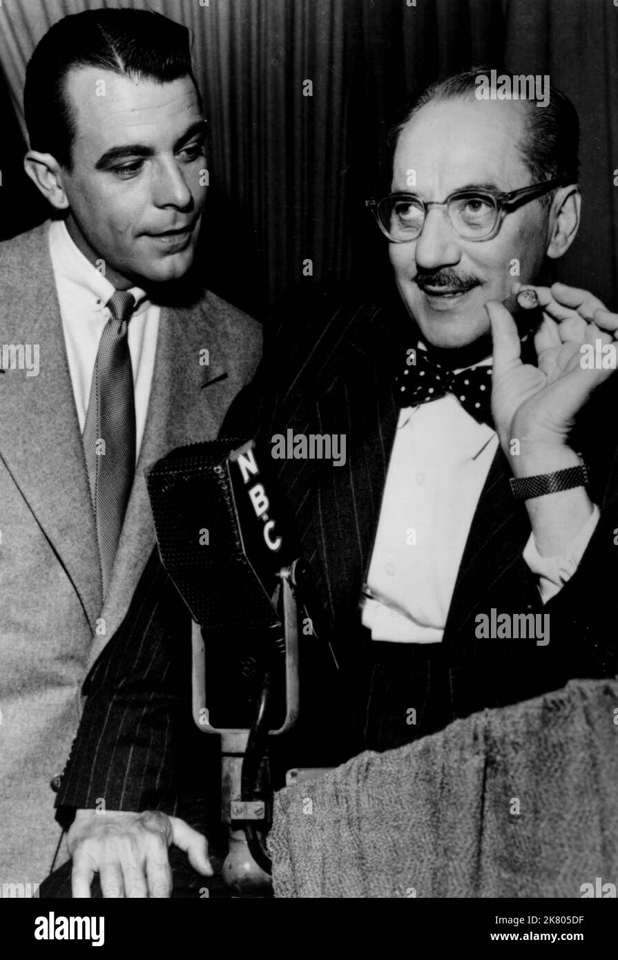 George Fenneman & Groucho Marx Television: You Bet Your Life (1957) 01. Mai 1955 **WARNUNG** dieses Foto ist nur für redaktionelle Zwecke bestimmt und unterliegt dem Urheberrecht von NBC und/oder dem Fotografen, der von der Film- oder Produktionsgesellschaft beauftragt wurde, und kann nur durch Veröffentlichungen in Verbindung mit der Werbung für den oben genannten Film reproduziert werden. Eine obligatorische Gutschrift an NBC ist erforderlich. Der Fotograf sollte ebenfalls angerechnet werden, wenn er bekannt ist. Ohne schriftliche Genehmigung der Film Company kann keine kommerzielle Nutzung gewährt werden. Stockfoto
